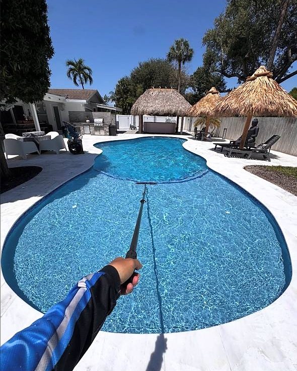 Manny brushing a freestyle pool in Fort Lauderdale on a clear day